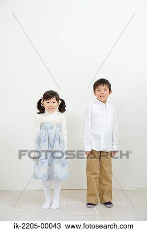 Stock Image - Siblings standing in a room. Fotosearch