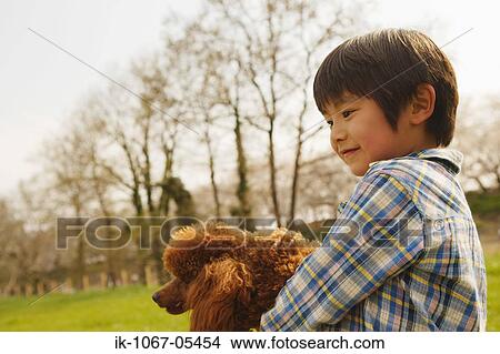 Picture - Smiling boy holding pet dog. Fotosearch