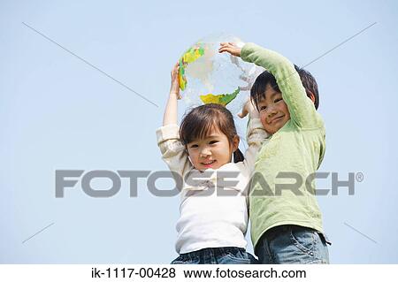 Stock Photo - Smiling children holding ball against blue sky. Fotosearch