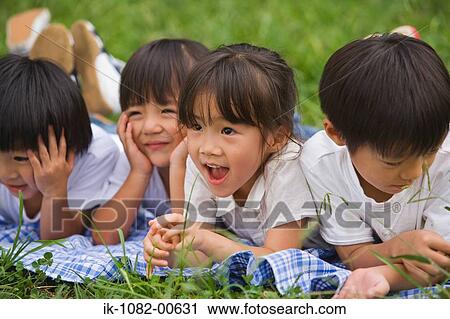 Smiling children lying on front together in park View Large Photo Image Stock Image - Smiling children lying on front together in park. Fotosearch