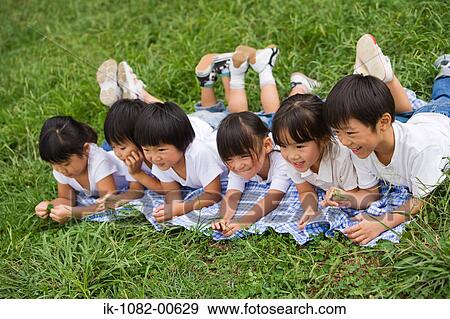 Smiling children lying on front together in park View Large Photo Image Stock Photo - Smiling children lying on front together in park. Fotosearch