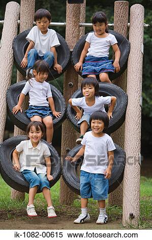 Smiling children sitting on tires climbing frame in park View Large Photo Image Stock Photography - Smiling children sitting on tires climbing frame in park. Fotosearch
