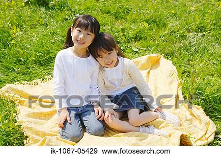 Stock Photo - Smiling children sitting together on grass. Fotosearch