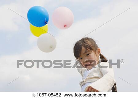 Stock Image - Smiling girl holding balloons. Fotosearch