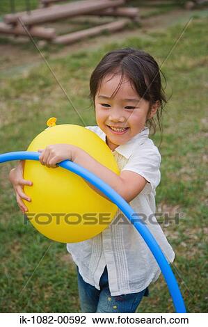 Smiling girl playing with balloon in park View Large Photo Image Stock Image - Smiling girl playing with balloon in park. Fotosearch