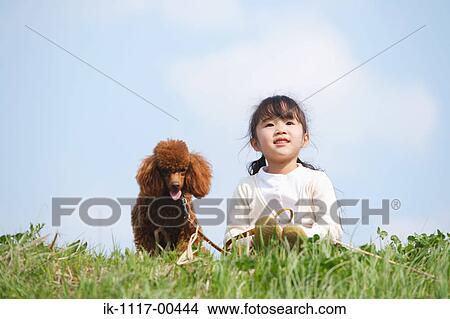 Smiling girl sitting with a cute puppy in park View Large Photo Image Picture - Smiling girl sitting with a cute puppy in park. Fotosearch