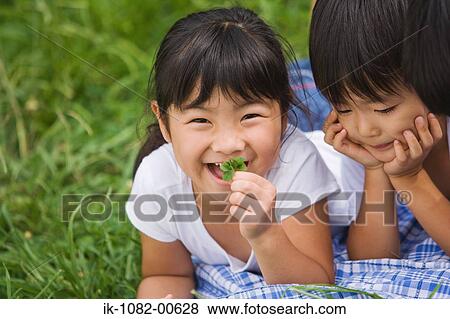 Smiling girls lying on front together in park View Large Photo Image Stock Photo - Smiling girls lying on front together in park. Fotosearch