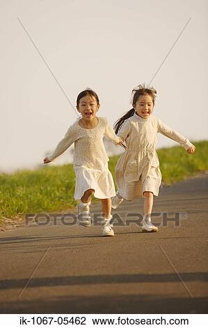 Smiling girls running on the road together View Large Photo Image Stock Image - Smiling girls running on the road together. Fotosearch