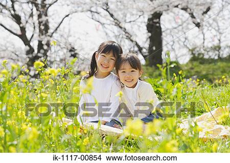 Smiling girls sitting together in a park View Large Photo Image Picture - Smiling girls sitting together in a park. Fotosearch