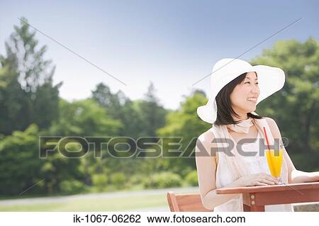 Smiling young woman having orange juice with straw View Large Photo Image Stock Image - Smiling young woman having orange juice with straw. Fotosearch