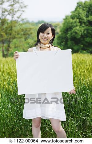 Smiling young woman holding board in wheat field View Large Photo Image Picture - Smiling young woman holding board in wheat field . Fotosearch