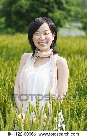 Smiling young woman standing in wheat field View Large Photo Image Stock Photography - Smiling young woman standing in wheat field . Fotosearch