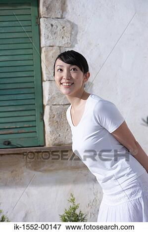 Stock Photo - Smiling young woman standing outdoors . Fotosearch