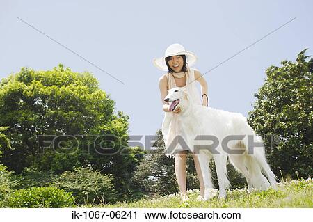 Smiling young woman with white dog in park View Large Photo Image Stock Image - Smiling young woman with white dog in park. Fotosearch