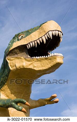 Stock Image - Statue of Dinosaur with Open Mouth against Blue Sky. Fotosearch