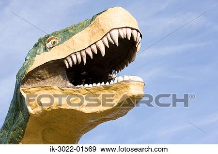 Stock Photo - Statue of Dinosaur with Open Mouth against Blue Sky. Fotosearch