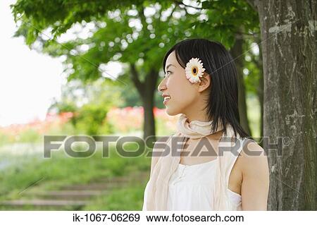 Thoughtful young woman standing by tree View Large Photo Image Stock Photo - Thoughtful young woman standing by tree. Fotosearch