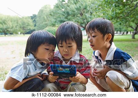 Picture - Three boys playing handheld videogame. Fotosearch