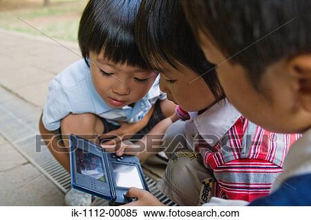 Three boys playing handheld videogame View Large Photo Image Stock Photography - Three boys playing handheld videogame. Fotosearch