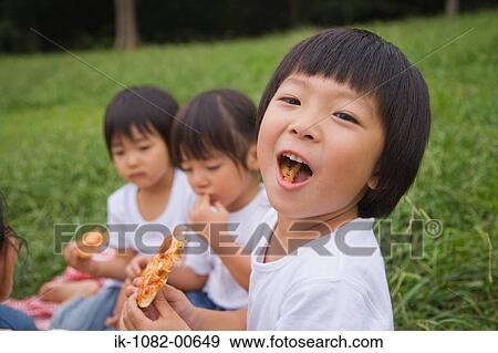 Three children enjoying eating pizza View Large Photo Image Stock Photo - Three children enjoying eating pizza. Fotosearch