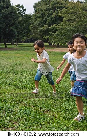 Three children playing together in a park View Large Photo Image Stock Image - Three children playing together in a park. Fotosearch