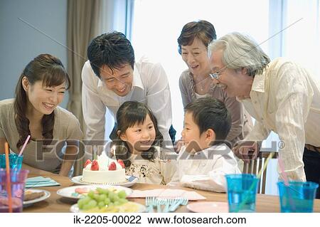 Stock Image - Three generation family celebrating birthday at home. Fotosearch