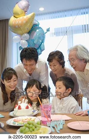 Stock Image - Three generation family celebrating birthday at home. Fotosearch
