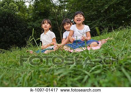 Stock Photo - Three girls enjoying sitting together in a park. Fotosearch