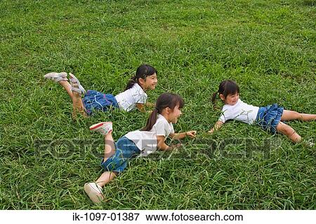 Stock Photo - Three girls lying on grass in a park. Fotosearch
