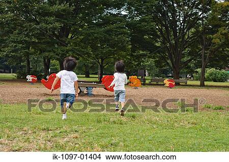 Two children running towards seesaw in a park View Large Photo Image Picture - Two children running towards seesaw in a park. Fotosearch