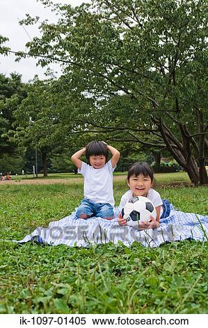 Two children sitting on a blanket in park View Large Photo Image Stock Photography - Two children sitting on a blanket in park. Fotosearch
