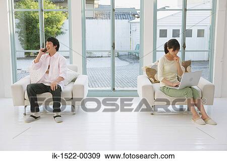 Stock Photo - Two People Using Phone and Laptop. Fotosearch