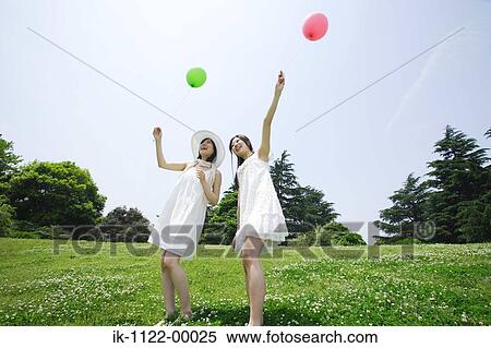 Stock Photography - Two young women holding balloons. Fotosearch