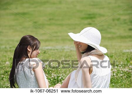 Two young women sitting in park View Large Photo Image Stock Image - Two young women sitting in park. Fotosearch