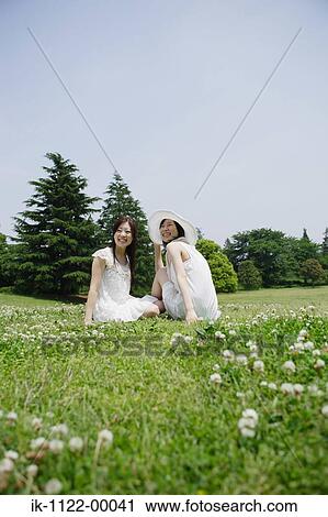 Two young women sitting in park View Large Photo Image Stock Image - Two young women sitting in park. Fotosearch