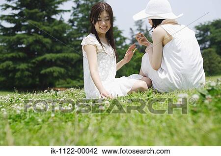 Two young women sitting in park View Large Photo Image Stock Image - Two young women sitting in park. Fotosearch