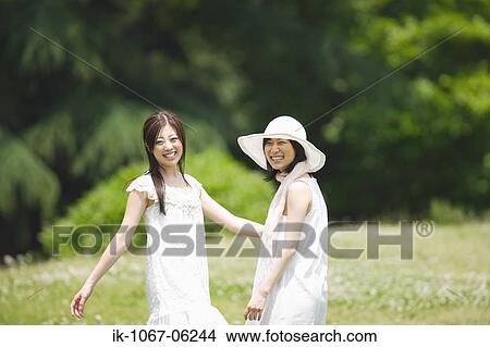 Two young women standing in park View Large Photo Image Picture - Two young women standing in park. Fotosearch