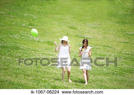 Picture - Two young women walking in park. Fotosearch