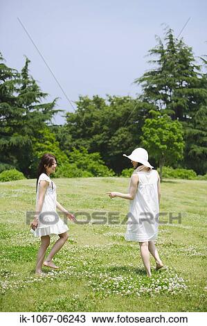 Two young women walking in park View Large Photo Image Stock Image - Two young women walking in park. Fotosearch