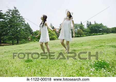 Two young women walking in park View Large Photo Image Stock Photo - Two young women walking in park. Fotosearch