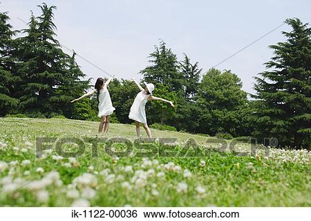 Two young women walking in park View Large Photo Image Stock Photograph - Two young women walking in park. Fotosearch