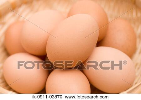 Stock Image - Uncooked brown eggs in a basket. Fotosearch