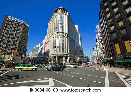 Stock Image - Vehicles intersecting at street with shopping malls. Fotosearch