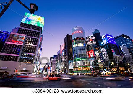 Stock Image - Vehicles on road with illuminated buildings. Fotosearch