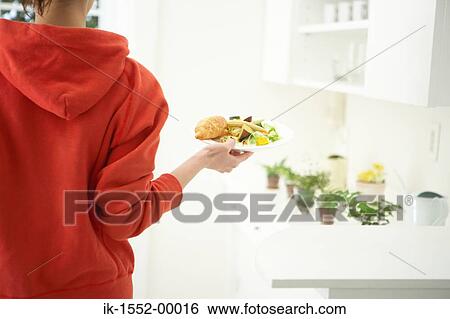 Stock Photograph - Woman holding a plate of snacks. Fotosearch