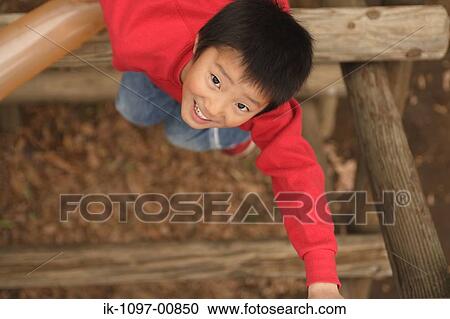 Stock Image - Young Boy Climbing on Wooden Jungle Gym. Fotosearch