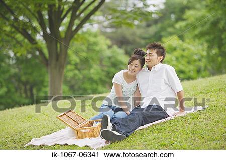 Stock Image - Young couple having picnic in park. Fotosearch