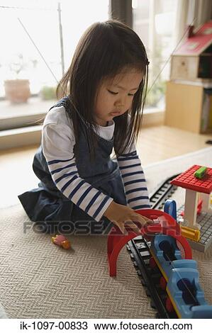 Stock Image - Young Girl Playing with Toy Trains. Fotosearch