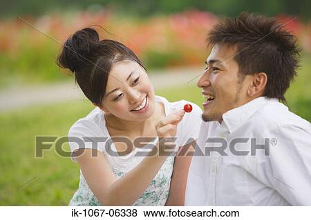 Stock Photo - Young Japanese couple feeding cherry. Fotosearch