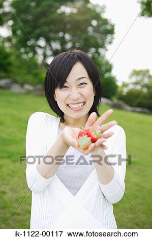 Stock Photo - Young smiling woman holding cherries. Fotosearch